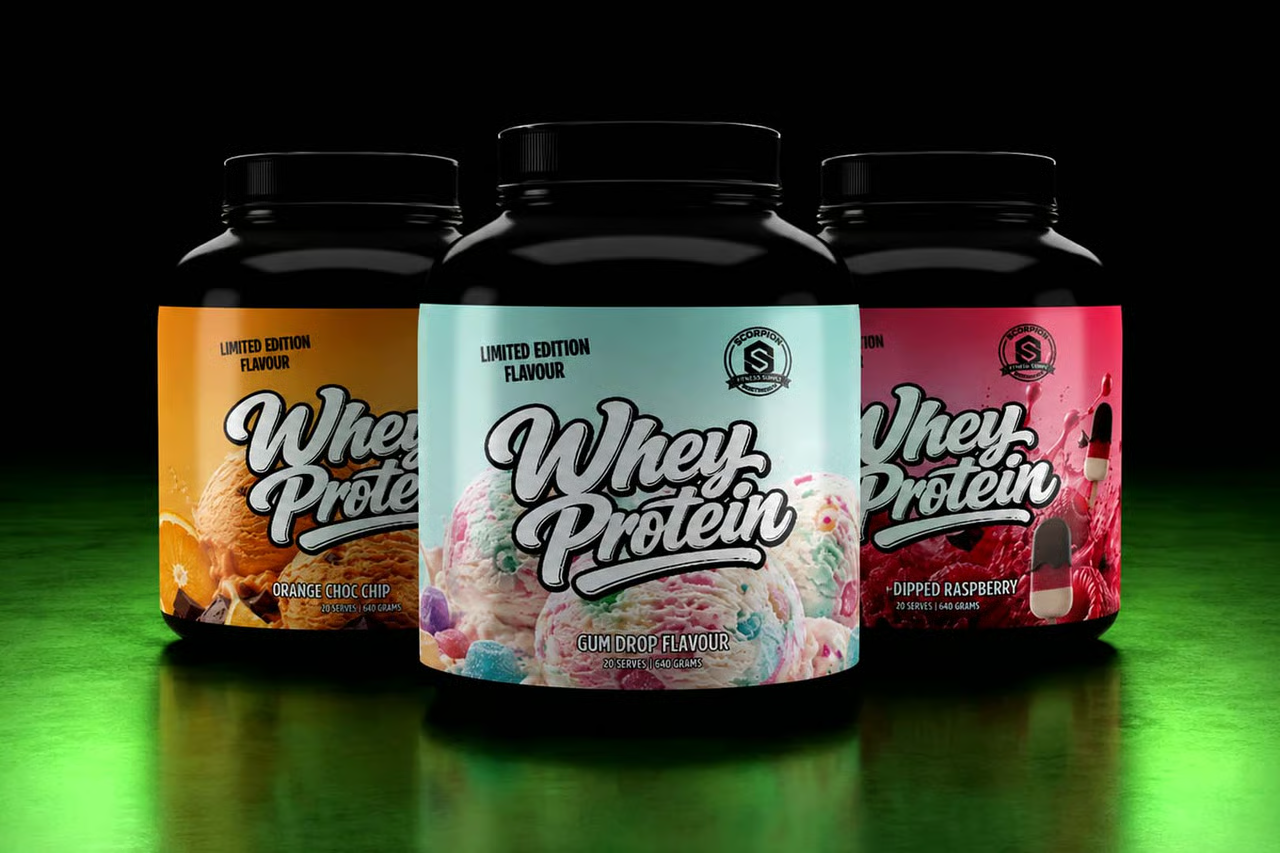 Three black tubs of Whey Protein powder arranged in a row on a black background with a green glow at the bottom. The center tub is almond milk flavor with a light blue label, flanked by orange and pink limited edition flavors.